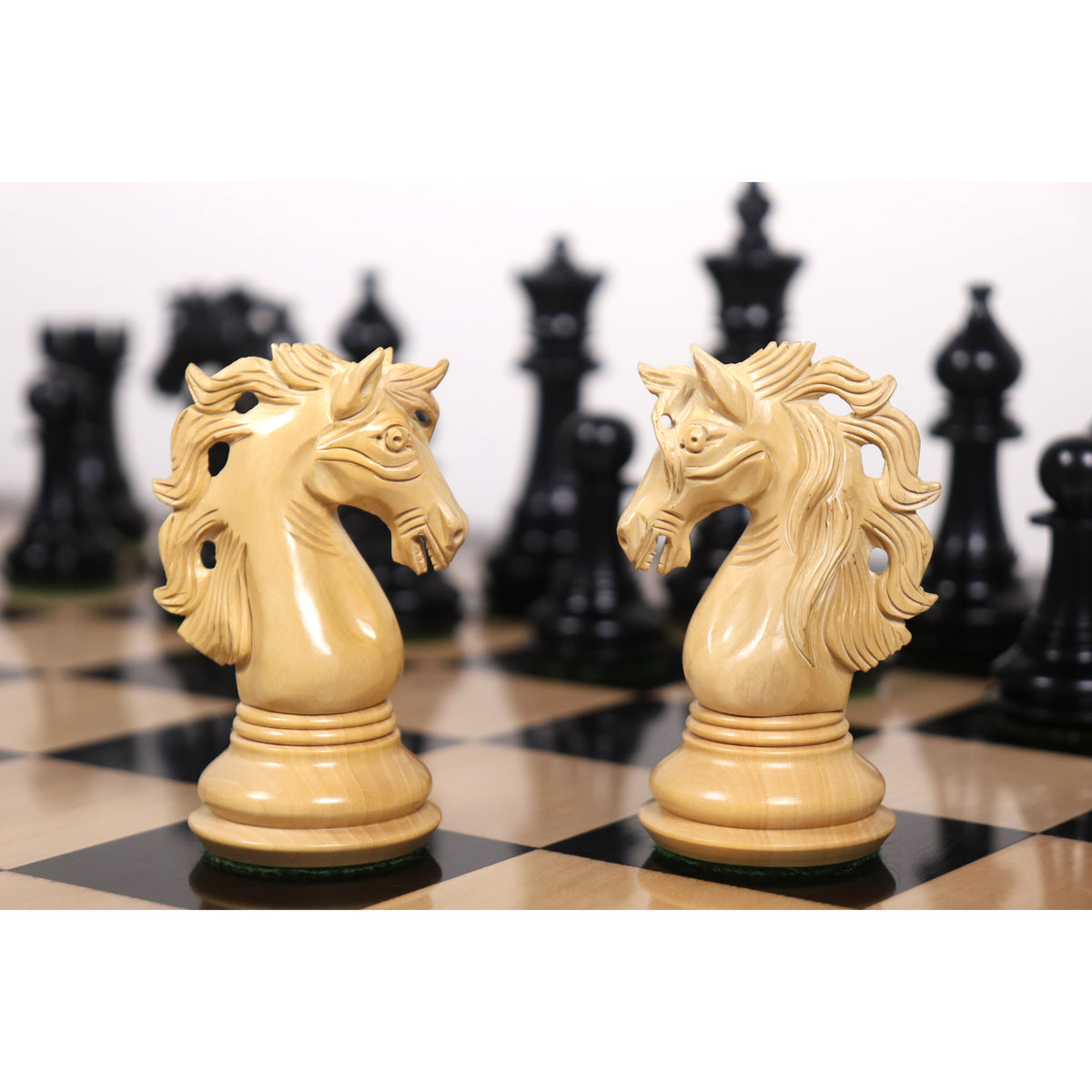 Two intricately carved Spartacus luxury Staunton knights facing each other on a chessboard.