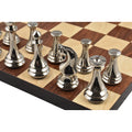 Close-up of silver polished luxury brass metal chess pieces arranged on a dark and light wooden board.