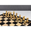 Natural boxwood Parker Staunton chess pieces arranged on a glossy black and natural wood grain chessboard.