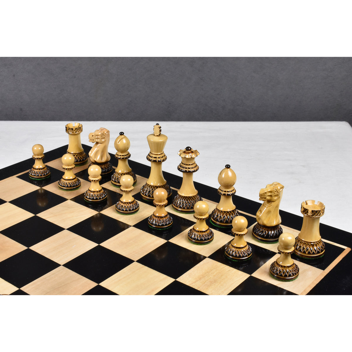 Natural boxwood Parker Staunton chess pieces arranged on a glossy black and natural wood grain chessboard.