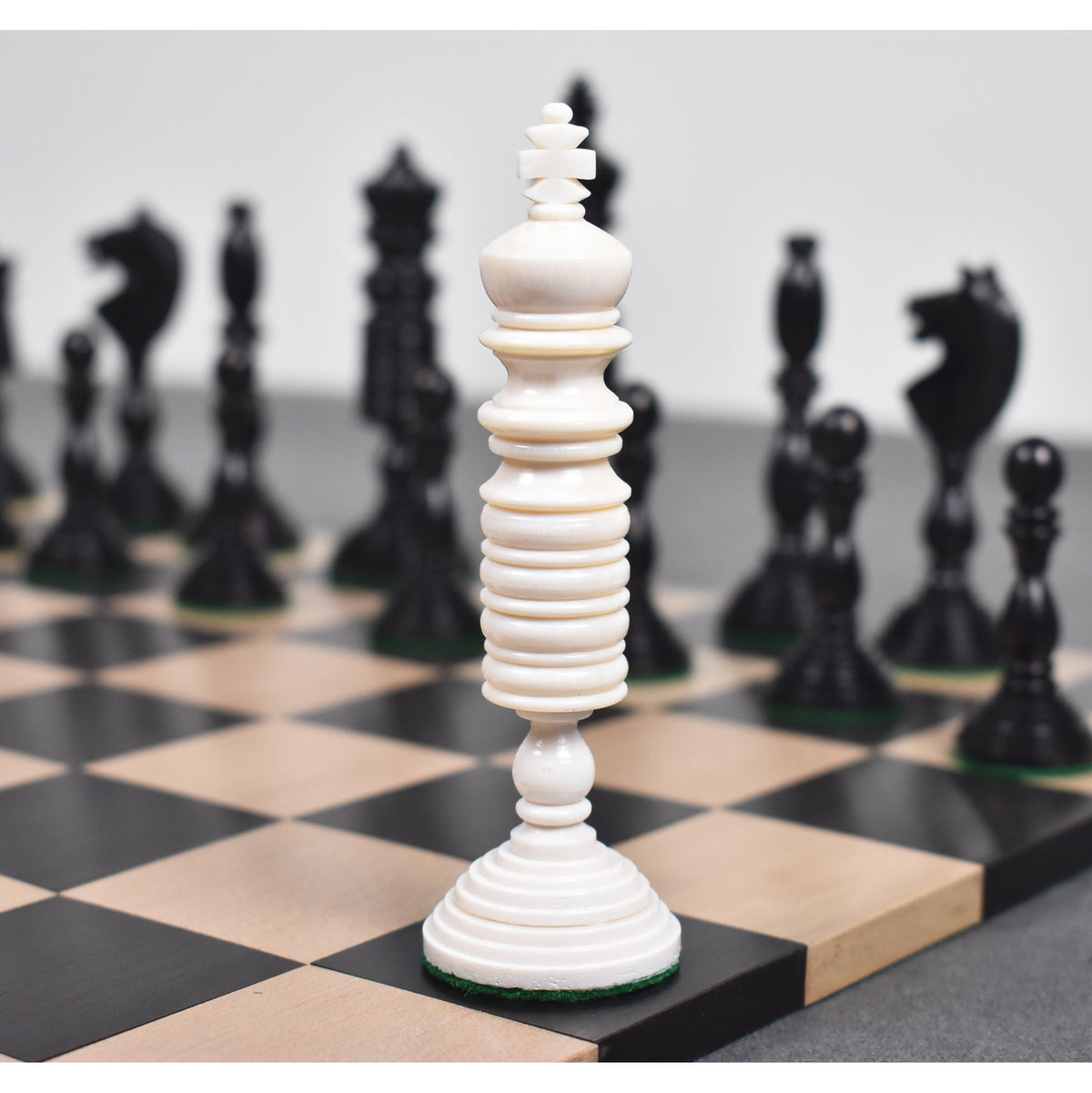 Close-up of a white antique pre-Staunton king piece on a wooden chessboard.