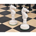 Two ivory white hand-carved camel bone knight chess pieces on a wooden chess board.