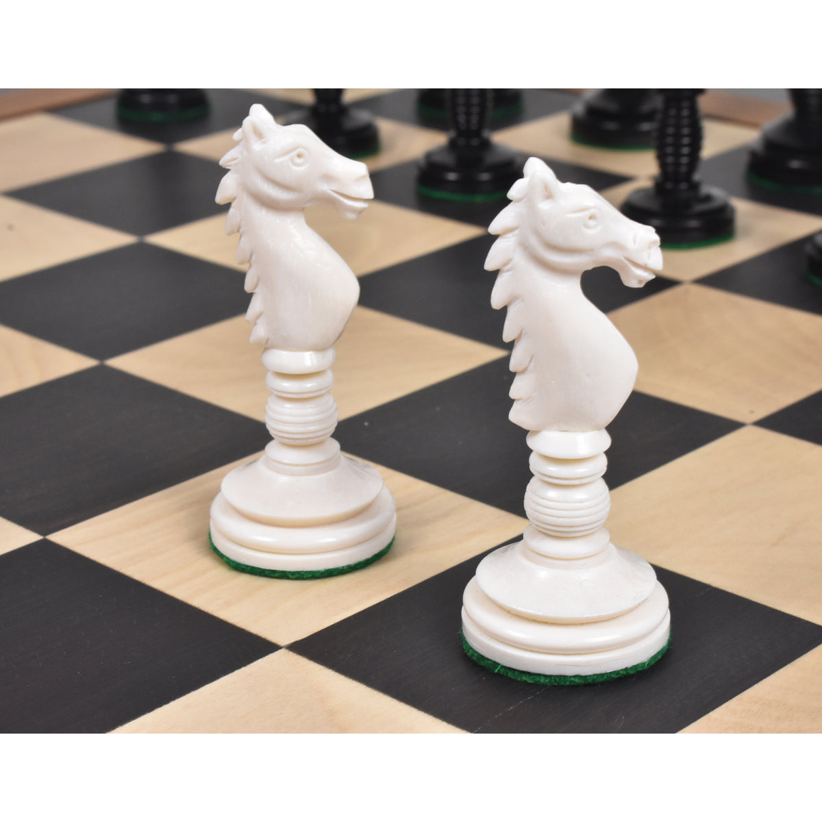 Two ivory white hand-carved camel bone knight chess pieces on a wooden chess board.