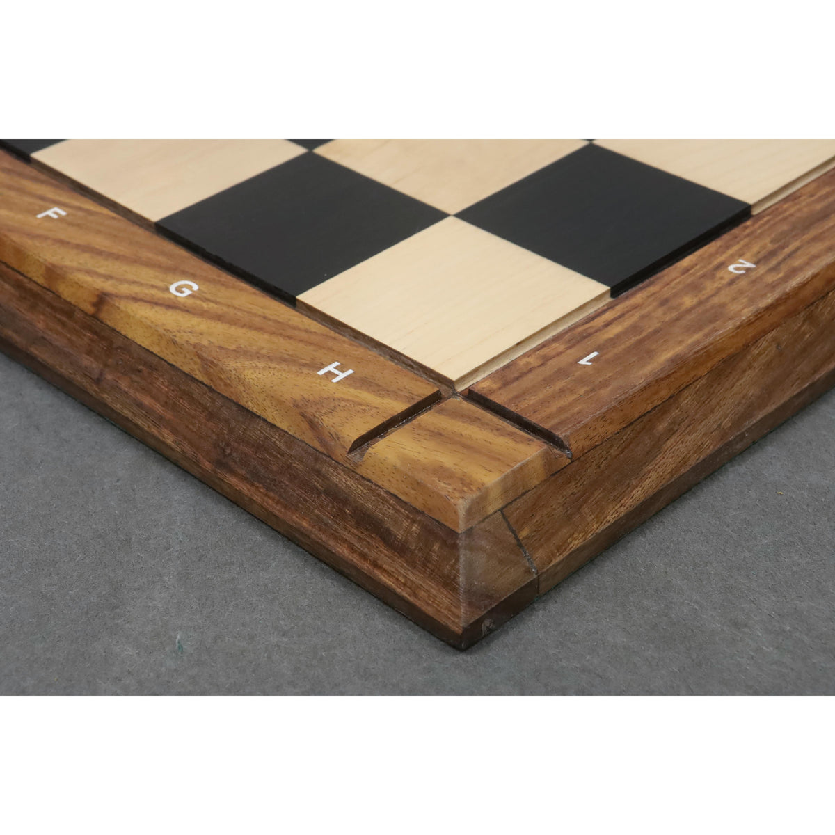 High-angle close-up of the mitered corner construction and algebraic notations on a luxury wooden chess board.