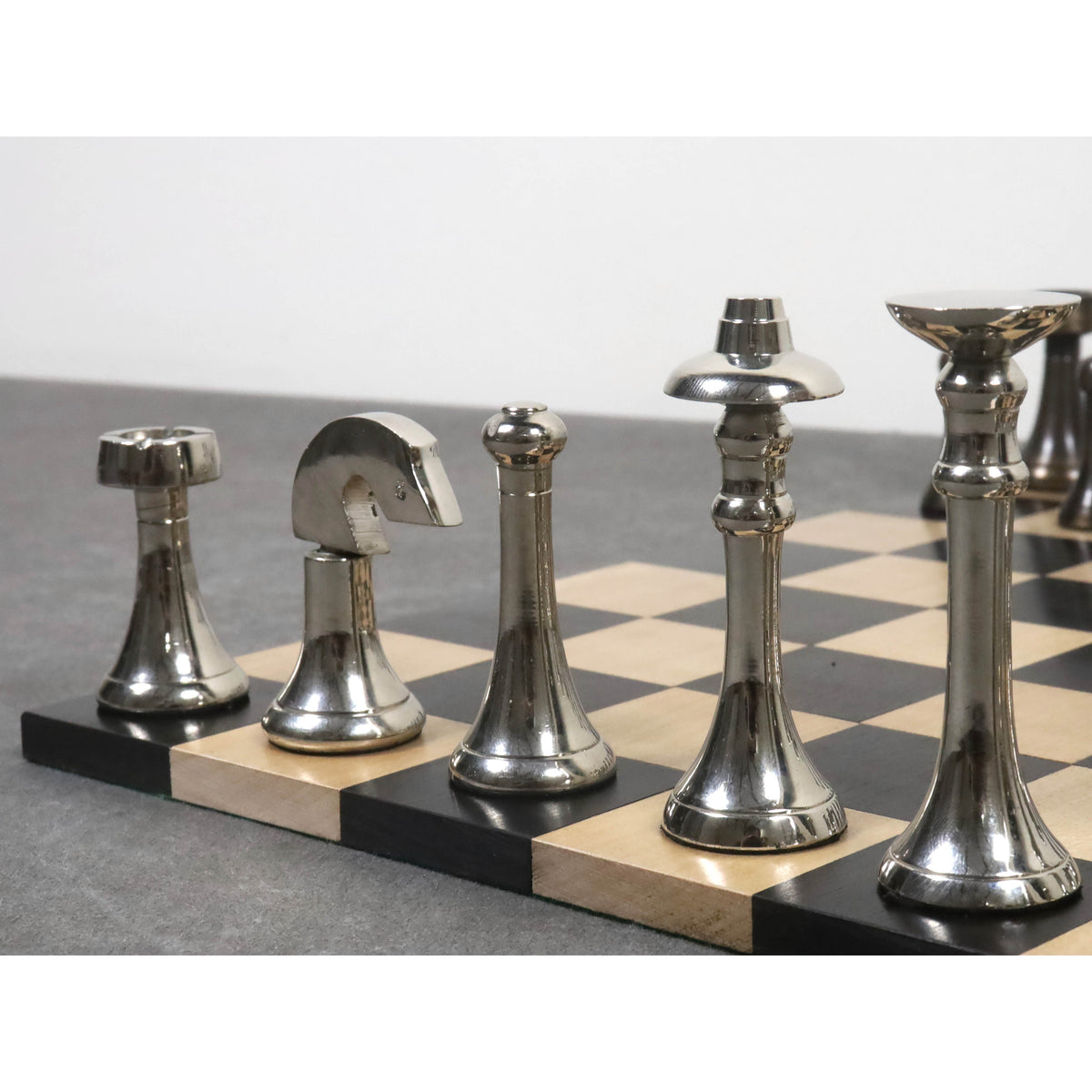 High-polished silver finish brass chess pieces including the King, Queen, and Knight on a marble board.
