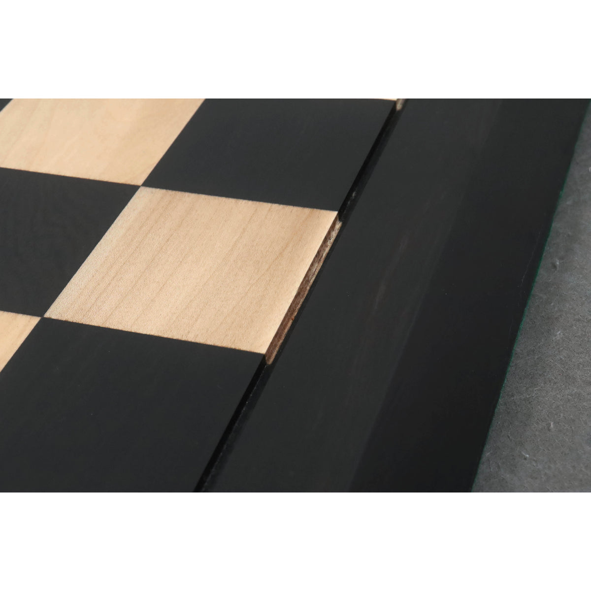 Detailed view of the precision wood inlay craftsmanship on an ebony and maple wood chessboard.