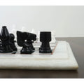 Detailed side view of handcarved black marble knight and rook chess pieces.