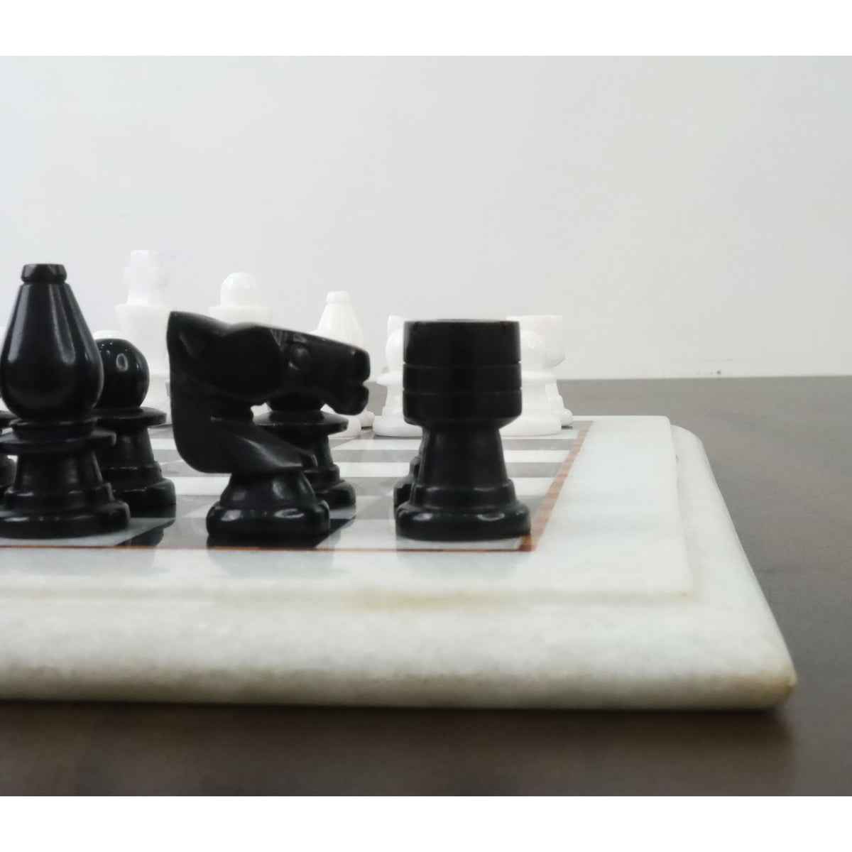 Detailed side view of handcarved black marble knight and rook chess pieces.