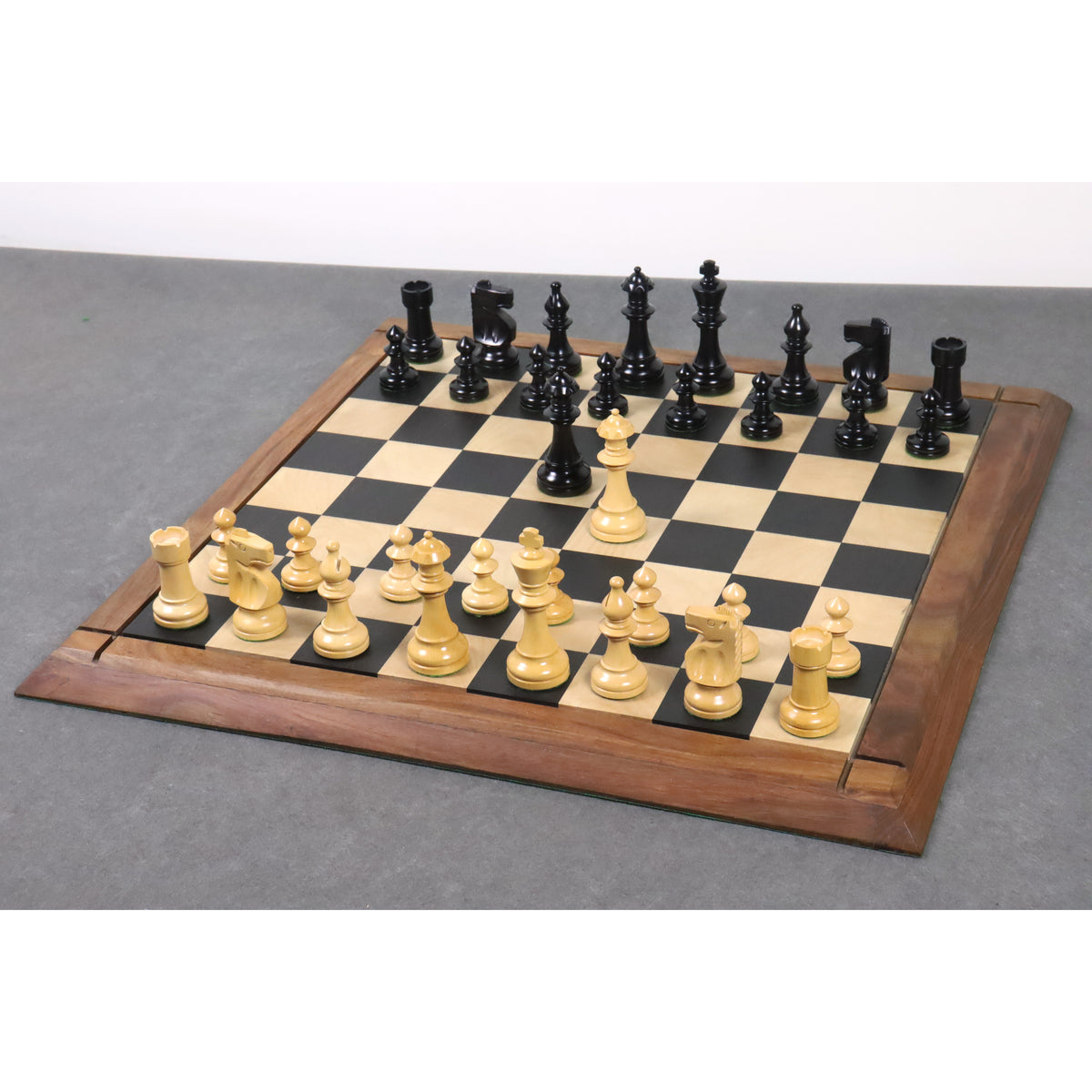 Weighted boxwood W.T. Pinney Staunton chess pieces fully set up for a game on a wooden chessboard.