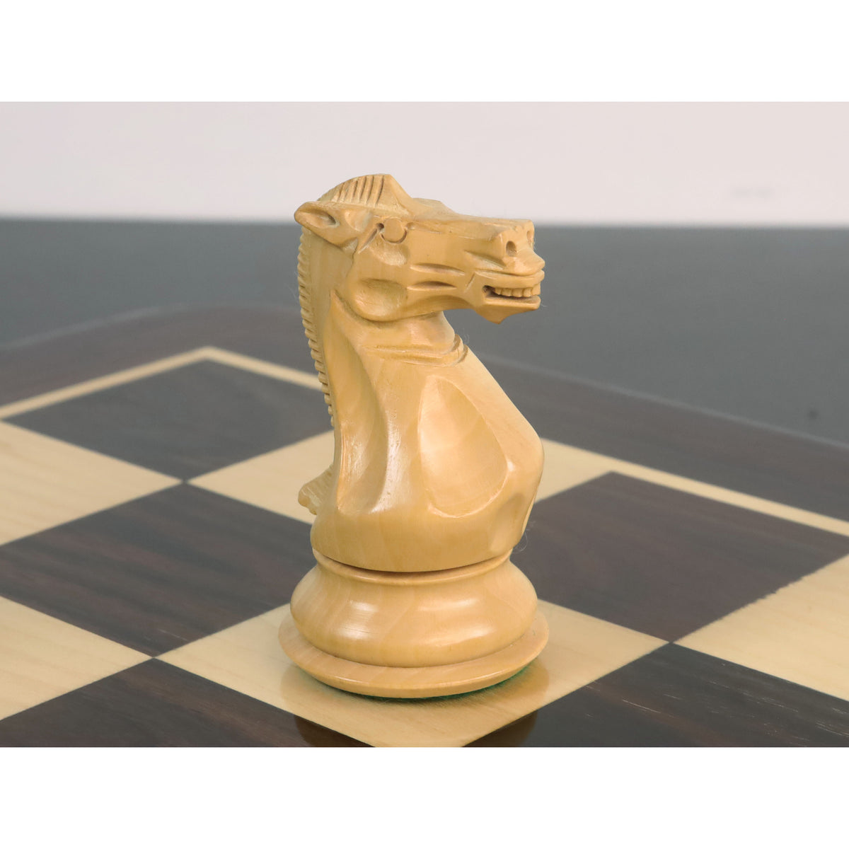 Detailed profile shot of a light boxwood knight from the sleek Staunton luxury chess set, showing its carved features.
