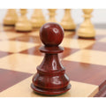 Polished bud rosewood pawn piece with distinct deep red and dark wood grain texture on a glossy chessboard.