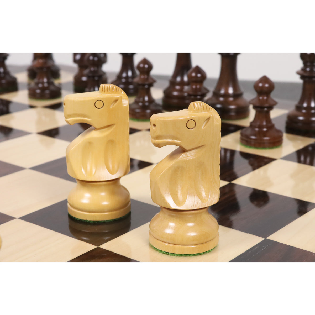 Two hand-carved boxwood knights from the Pinney Staunton set arranged on a polished chessboard.