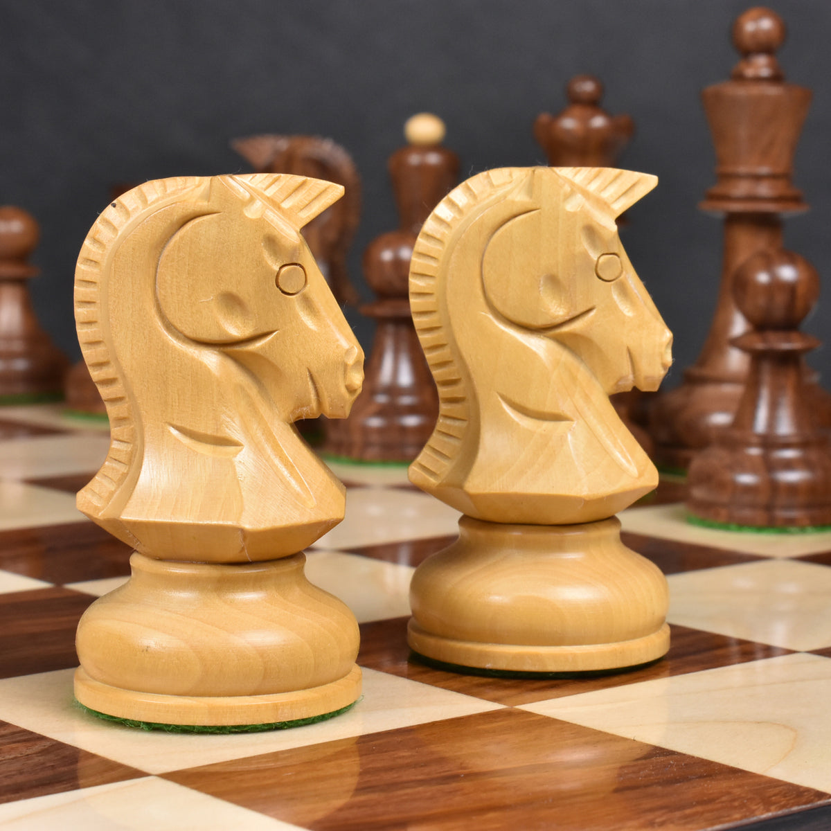 Profile close-up of two hand-carved Boxwood Knights from the 1970s Dubrovnik chess set on a board.