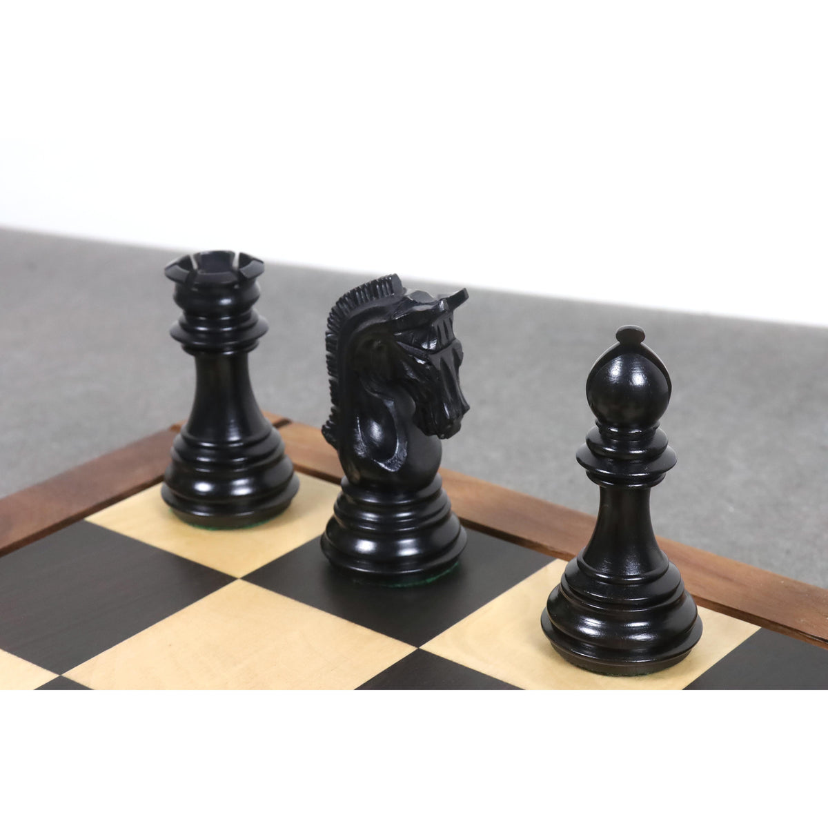 Dark rook, knight, and bishop from the 3.8" Imperial Staunton ebony chess pieces set closely framed on a chessboard.