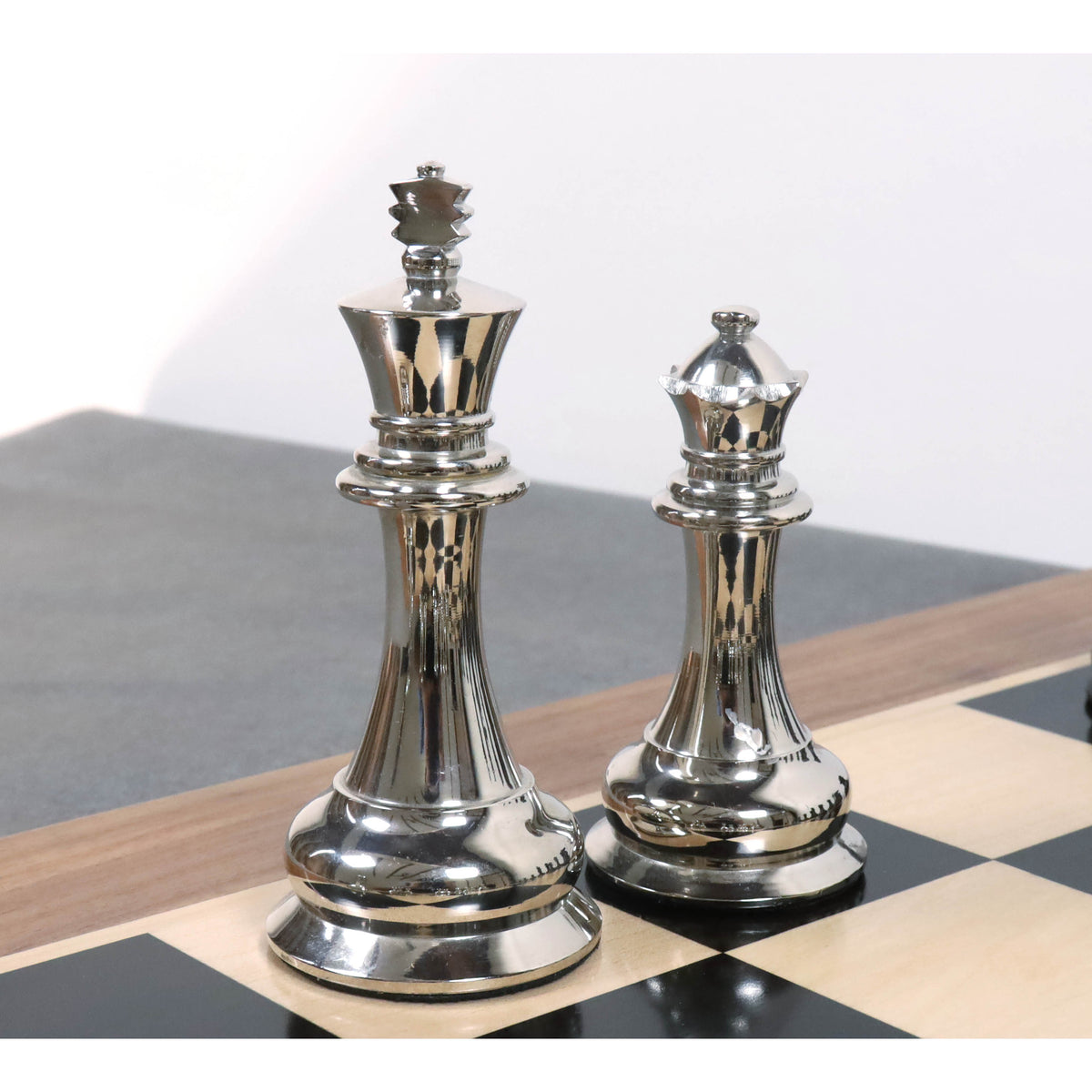 Gleaming silver brass metal king and queen chess pieces showcasing detailed 1849 Staunton craftsmanship.