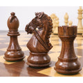 Handcrafted golden rosewood bishop, knight, and rook chess pieces showcasing natural wood grain.