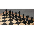 Two rows of glossy black lacquered wooden chess pieces arranged on a wooden chessboard.