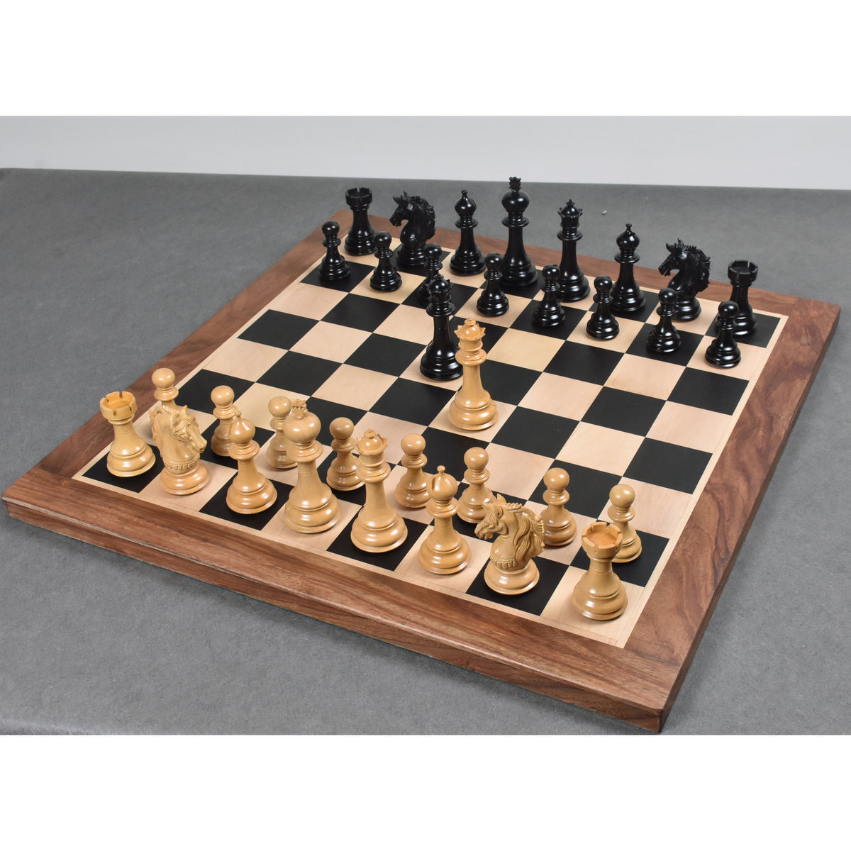 Ebony and boxwood chess pieces arranged gracefully on a black leatherette storage coffer box over a chessboard.