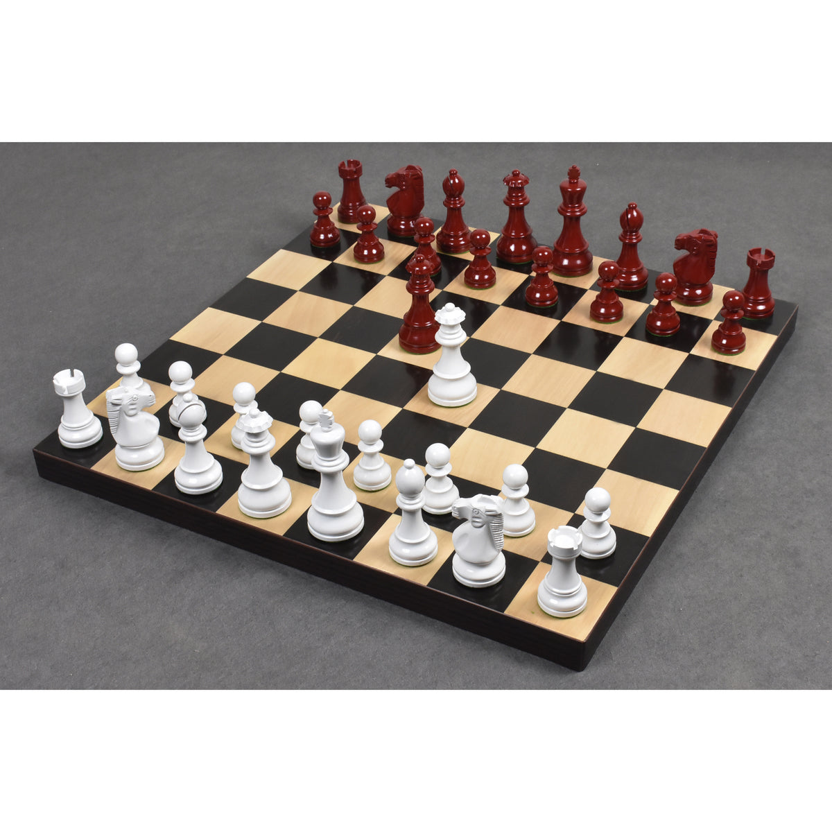 Burgundy and white lacquered boxwood Prime Staunton chess pieces fully set up for a game on a wooden chessboard.