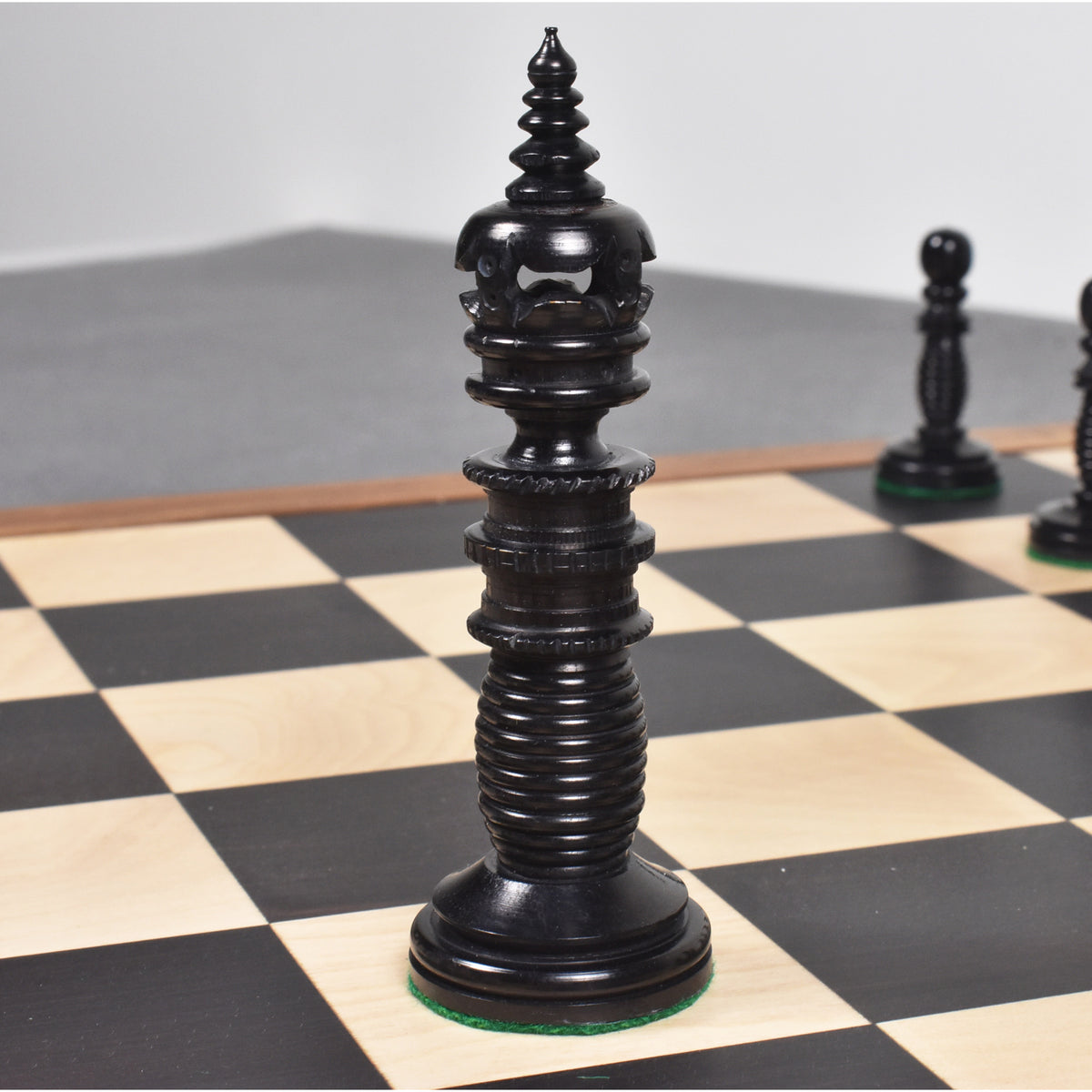 Close-up of a black Minaret series hand-carved camel bone king chess piece on a board.