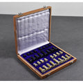 Open wooden storage case with plush blue velvet lining and neatly packed soapstone chess pieces.