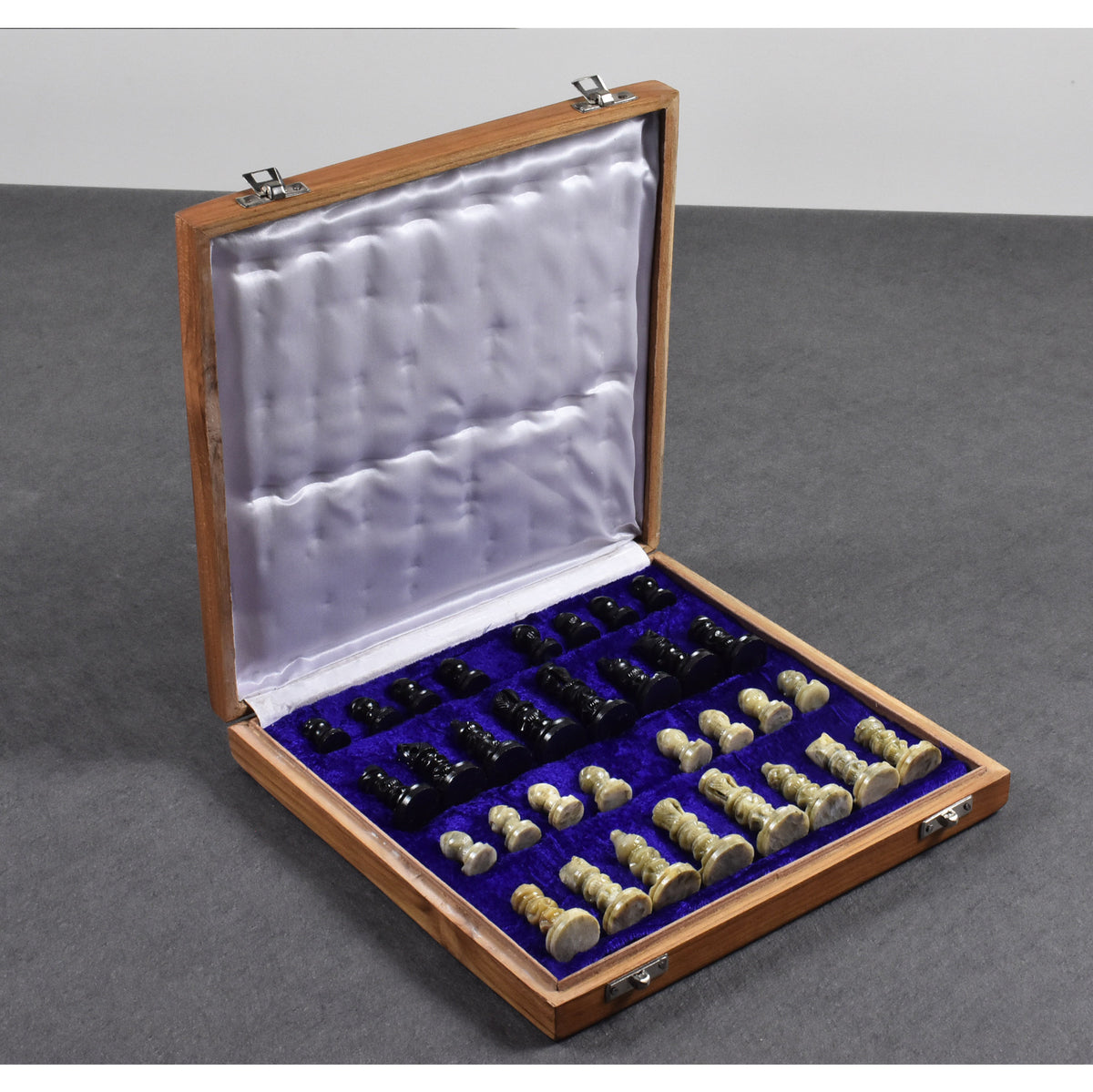 Open wooden storage case with plush blue velvet lining and neatly packed soapstone chess pieces.