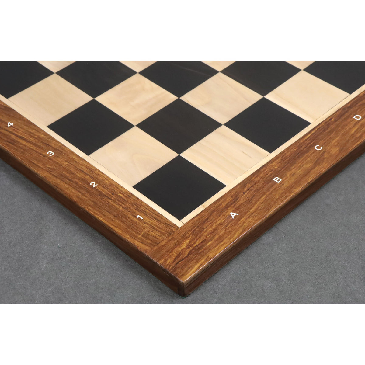High-angle close-up of the border craftsmanship and matte finish on an Ebony and Maple chessboard.