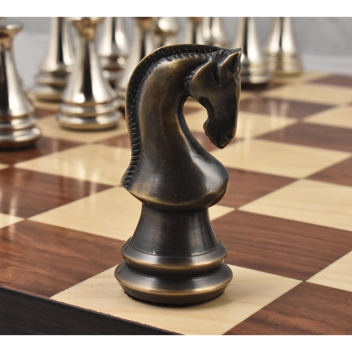Detailed close-up of a 4.4 inch antique brass metal luxury chess knight piece on a wooden square.
