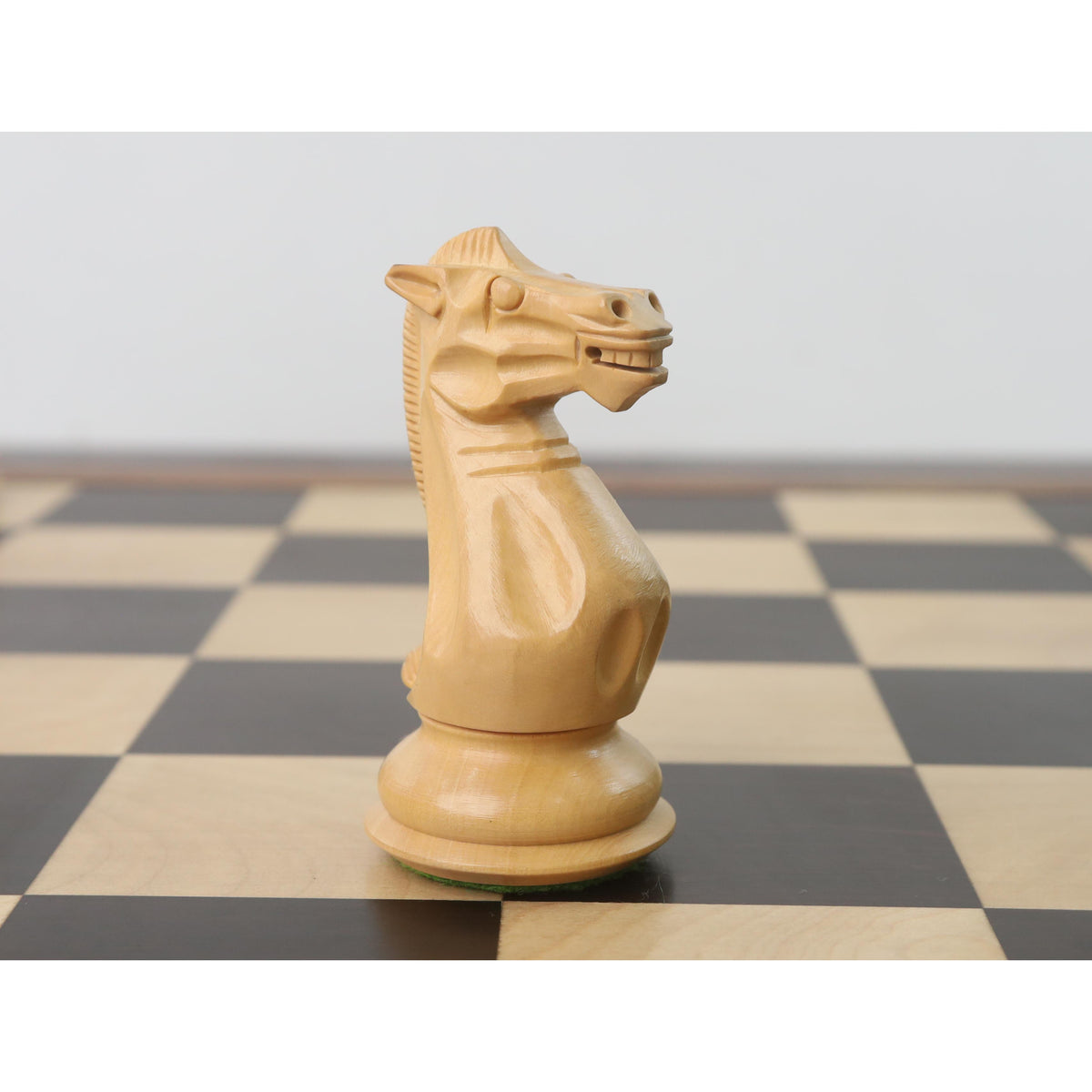 Side profile view of a wooden white Staunton knight chess piece.