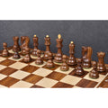 Golden rosewood chess pieces arranged on a wooden chessboard against a dark textured background.