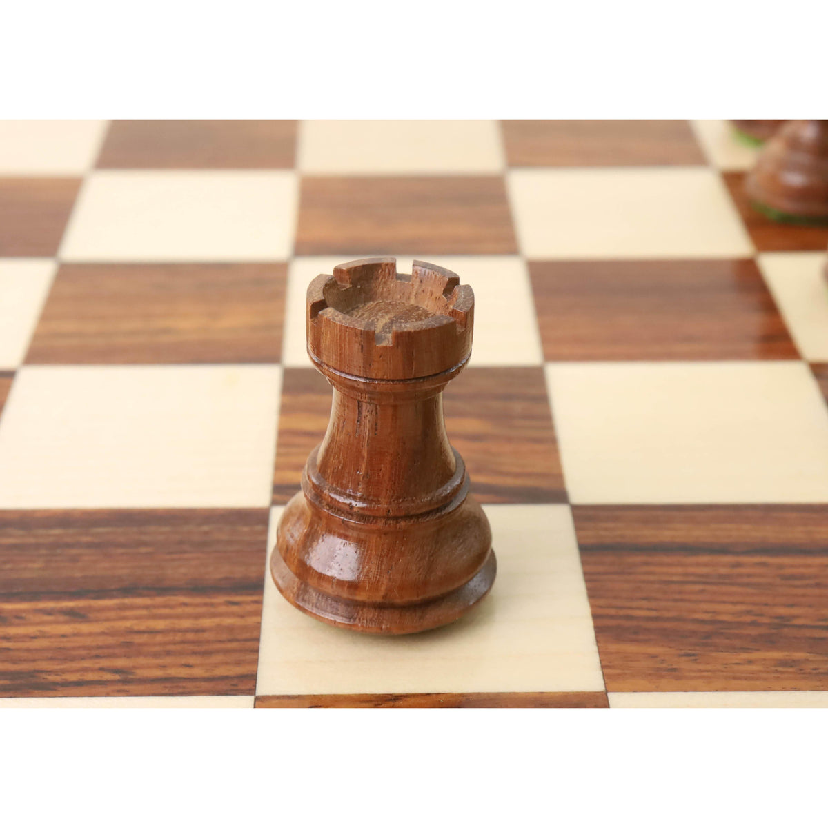 Handcrafted Golden Rosewood rook from the Zagreb collection on a polished wooden chessboard.