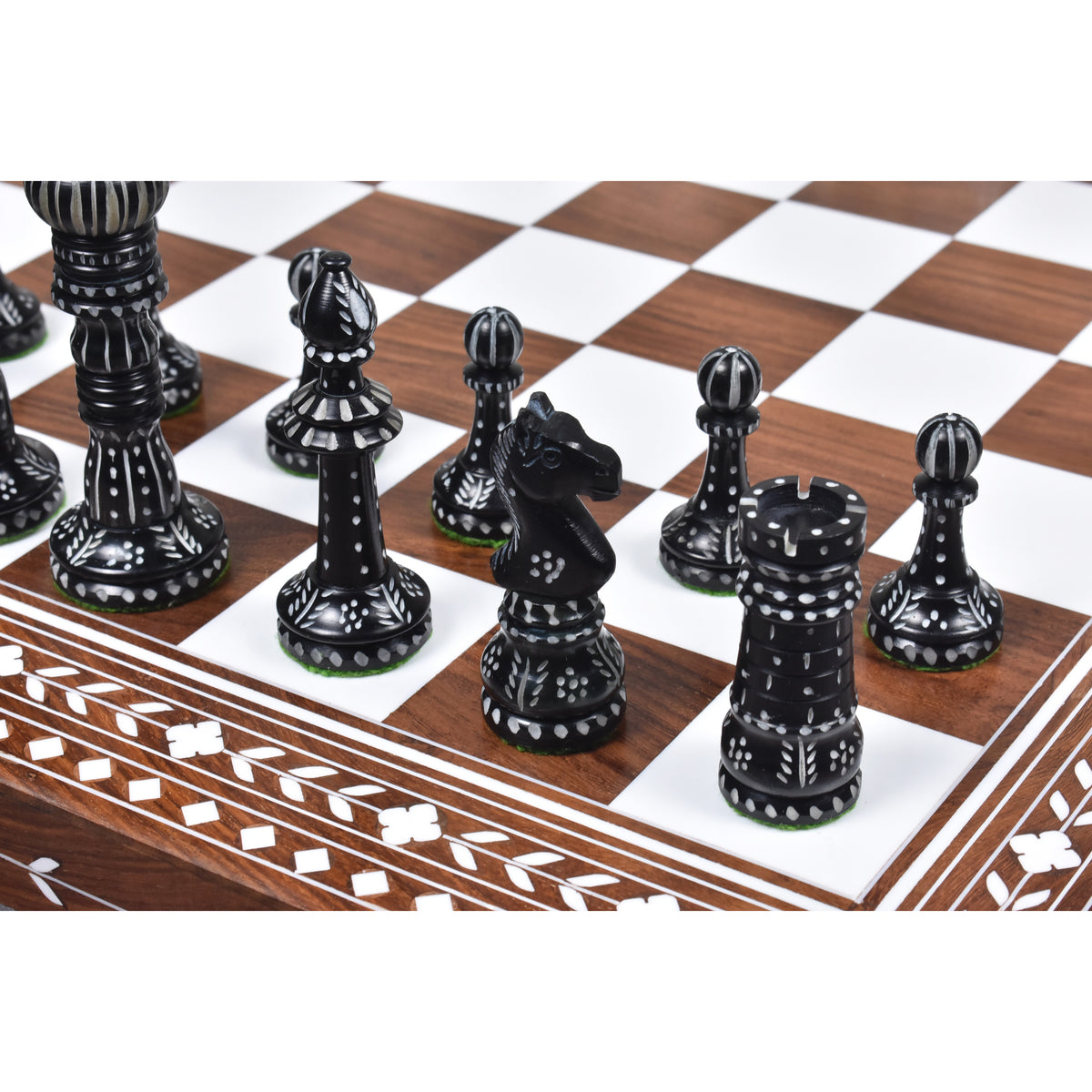 Hand-carved black camel bone chess pieces on an inlaid wooden board.