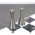 Two sleek, silver-finished brass chess pieces standing on a black and white marble chess board square.