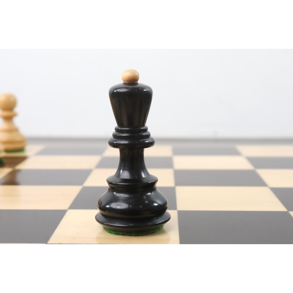 Ebonised boxwood Zagreb queen featuring a natural wood finial and elegant Staunton-style curves.