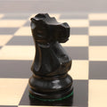 Close-up profile of a single ebonised boxwood knight from the Reykjavik Series Staunton chess set on a board.
