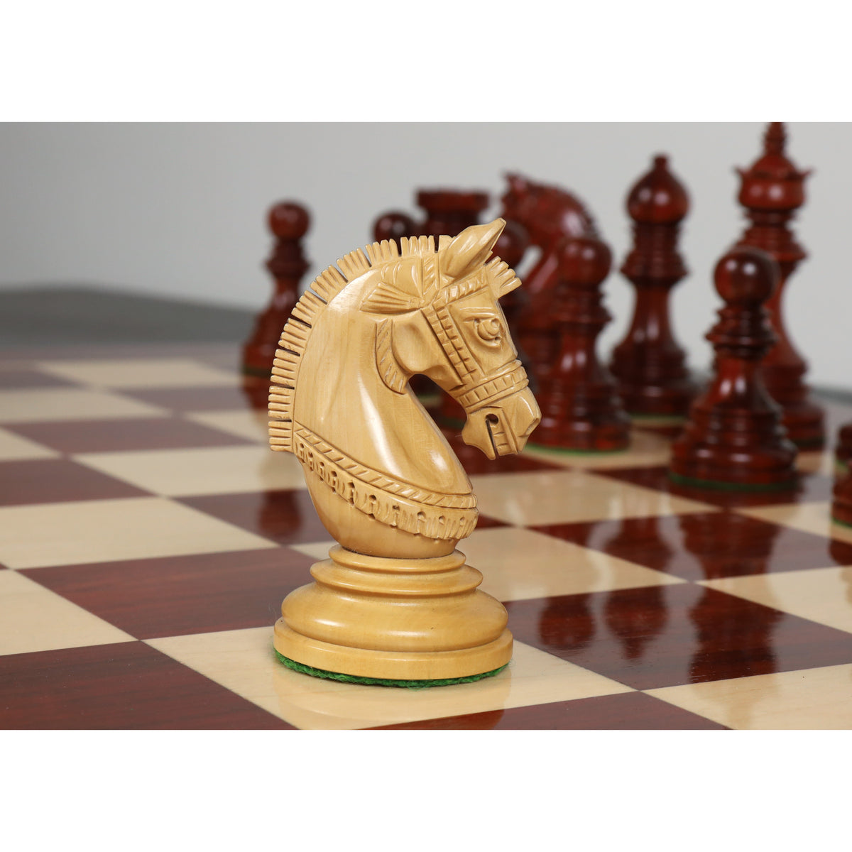 Hand-carved light Boxwood Staunton knight on a premium wooden chessboard.