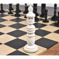 Intricately carved ivory white camel bone king chess piece from the Minaret series on a board.