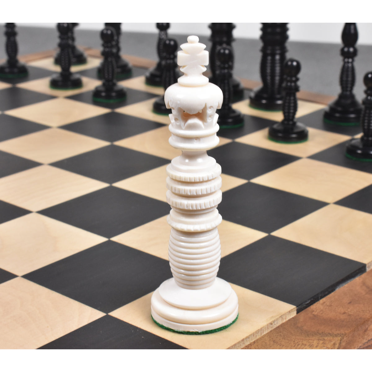 Intricately carved ivory white camel bone king chess piece from the Minaret series on a board.