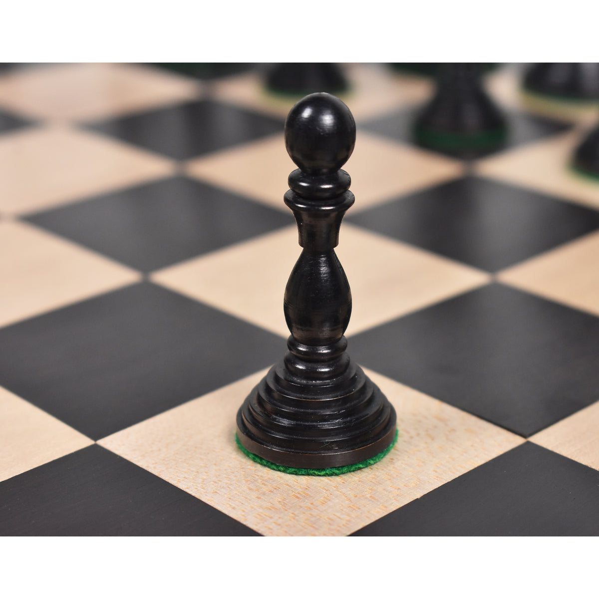 Black antique pre-Staunton pawn chess piece on a wooden chessboard.