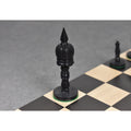 Close-up of the black dyed camel bone King piece on a wooden chessboard.