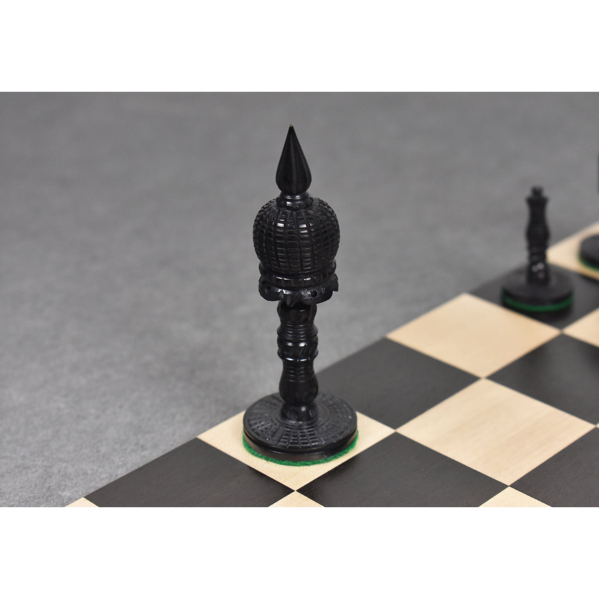 Close-up of the black dyed camel bone King piece on a wooden chessboard.