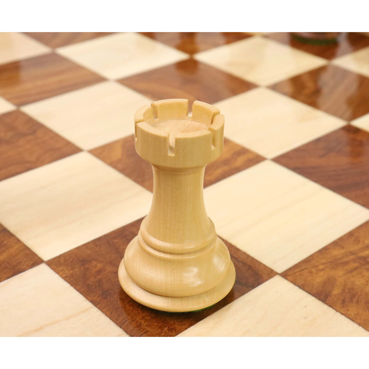 Close-up detailing the battlements of a boxwood British Staunton rook resting on a chessboard.