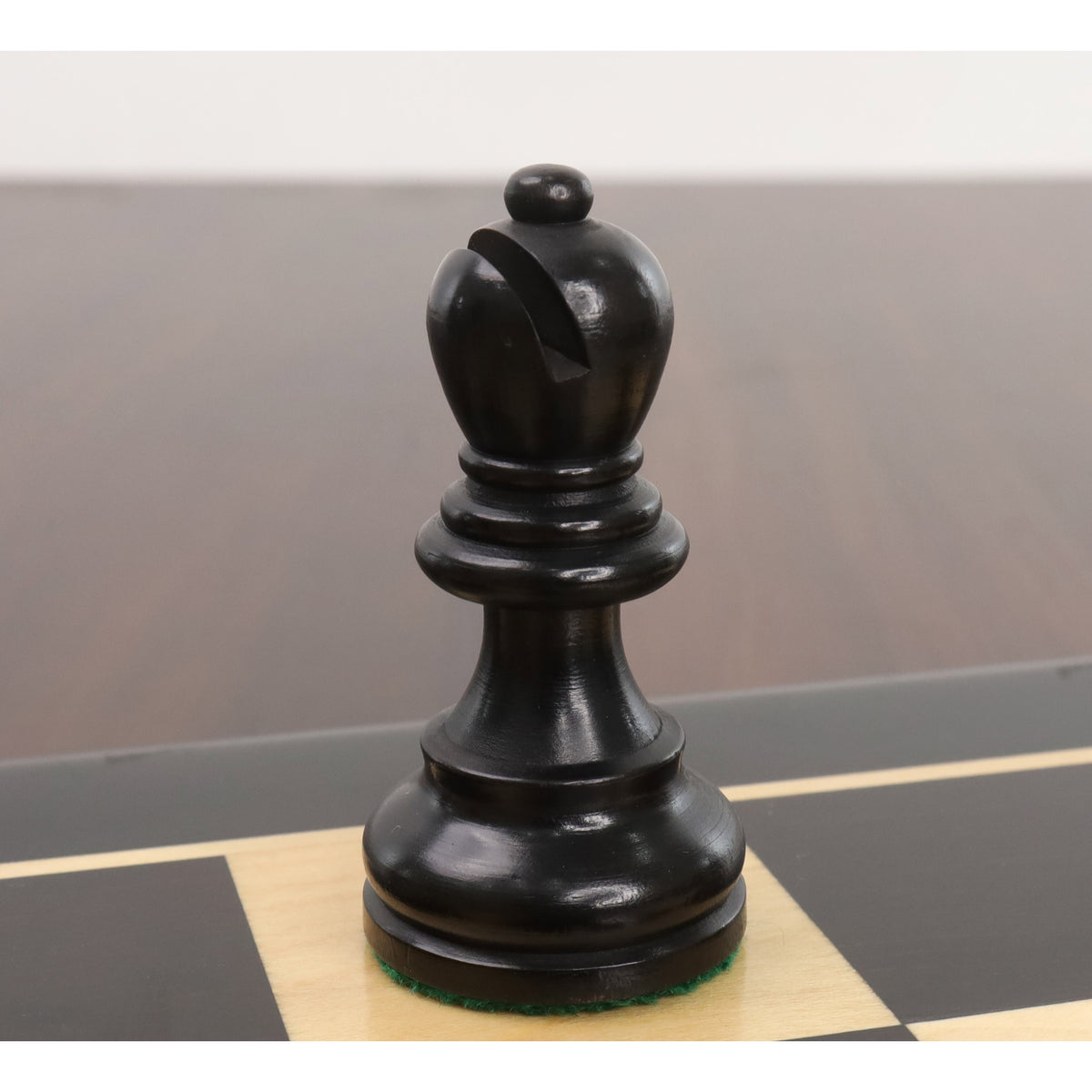 Close-up of a single ebonised boxwood rook from the Reykjavik Series Staunton chess set on a board.