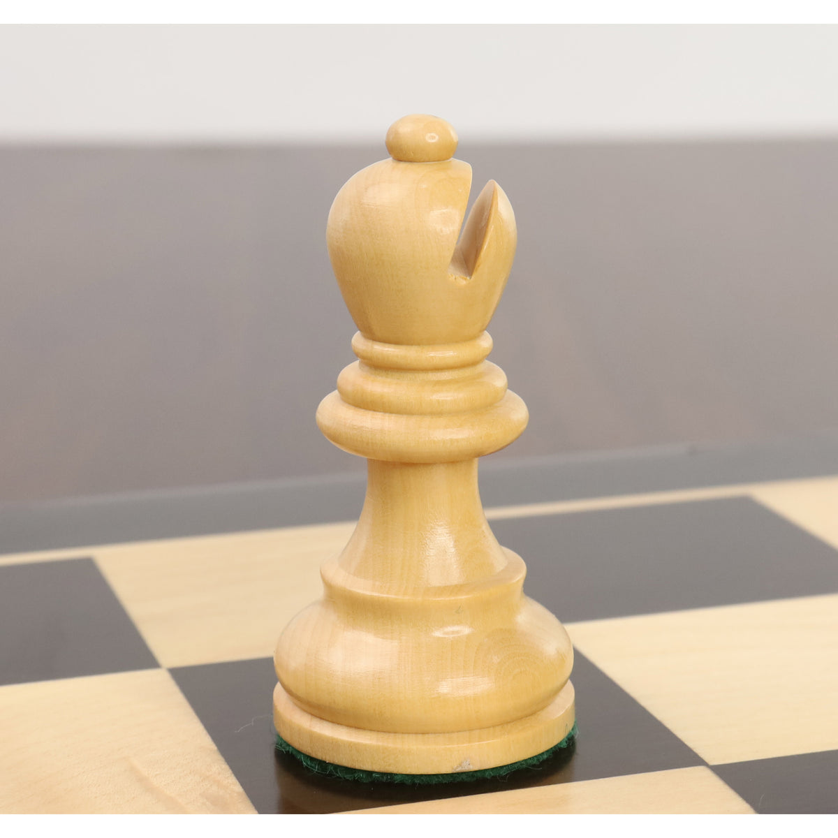 Close-up of a single natural boxwood rook from the Reykjavik Series Staunton chess set on a board.