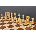Boxwood chess pieces aligned on a wooden board with a dark slate background backdrop.