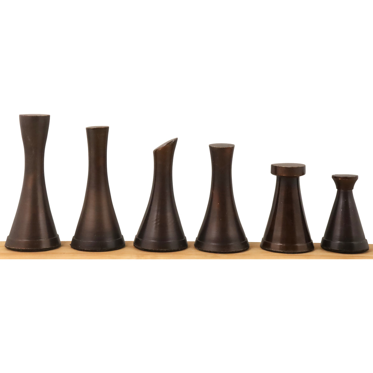 Six dark brown minimal brass tower chess pieces lined up in a row on a light-colored wooden stand.