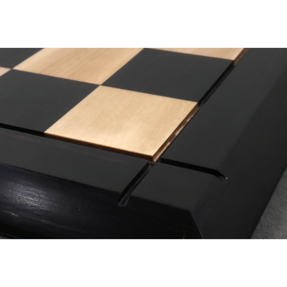 Close-up showing the precise routed groove and finish on the border of a premium ebony chessboard.