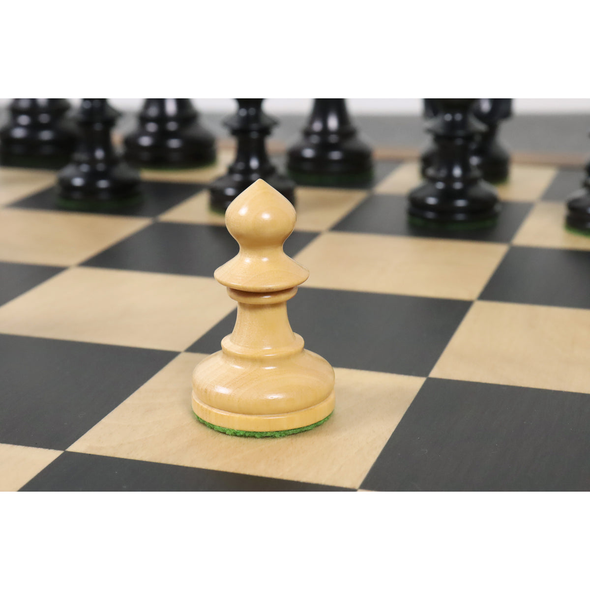 A single natural boxwood W.T. Pinney Staunton pawn resting on a wooden chessboard square.