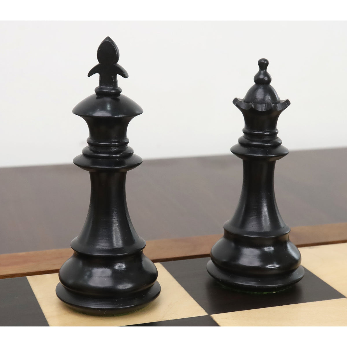Black king and queen pieces from the 3.7" British Staunton ebonised boxwood chess set on a board.