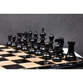 A set of dark ebonised boxwood executive staunton pieces placed on a board.